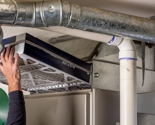 An arm reaching up replacing a furnace filter