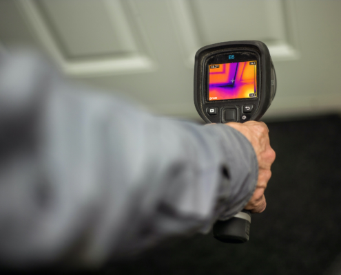 A home inspector using an infrared camera to check the door for drafts
