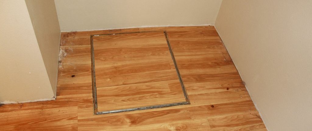 An access hatch to a crawlspace located inside a building.