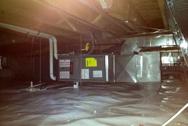 A crawl space with installed heat ducts, heating source, and a cold air return vent, illustrating efficient heating system configuration.