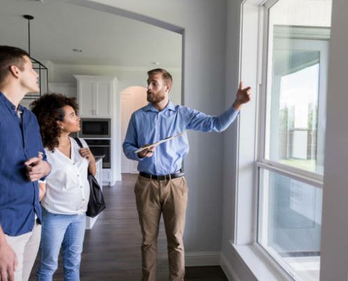 Confident home inspector shows potential homeowners the living room windows in the home.