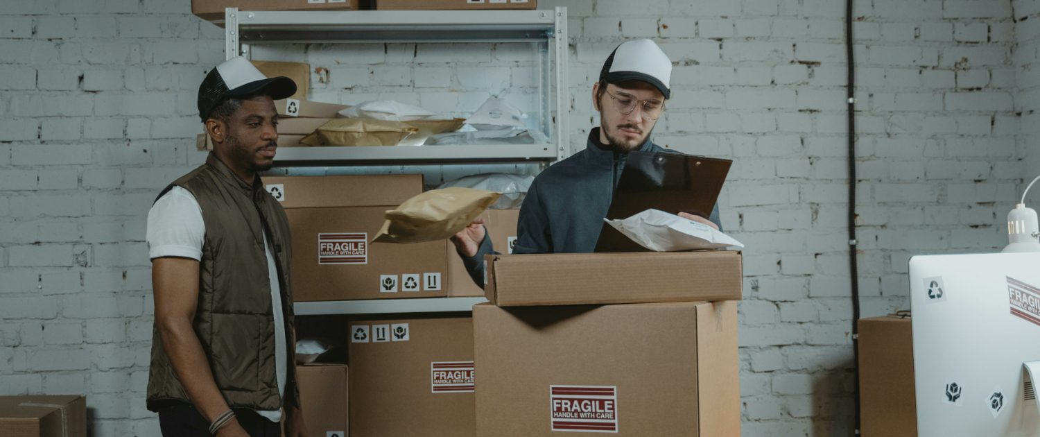 Two men standing next to cardboard boxes