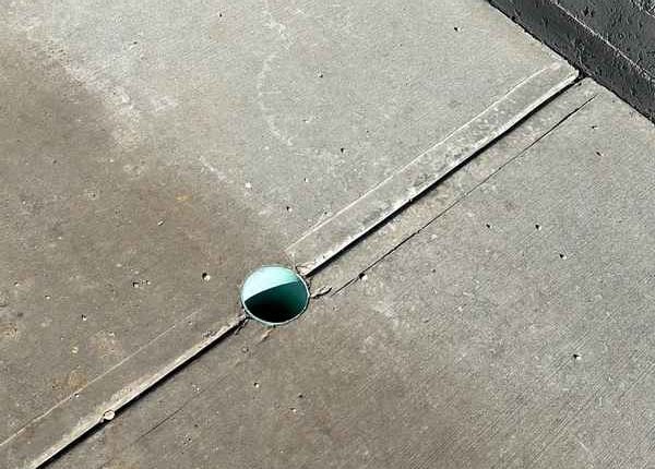 A water shut-off valve clearly visible on a concrete driveway.