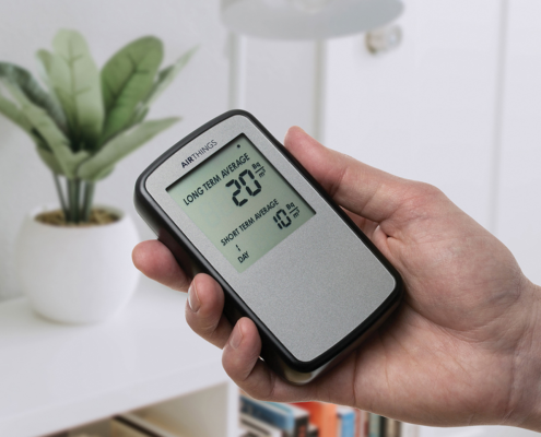 Hand holding an AirThings Corentium Home continuous radon monitor